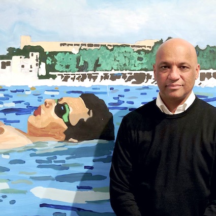 Autograph's Director Mark Sealy stood in front of a painting by Sharif Persaud. The painting is of a man floating in the seaAutograph's Director Mark Sealy stood in front of a painting by Sharif Persaud. The painting is of a man floating in the sea