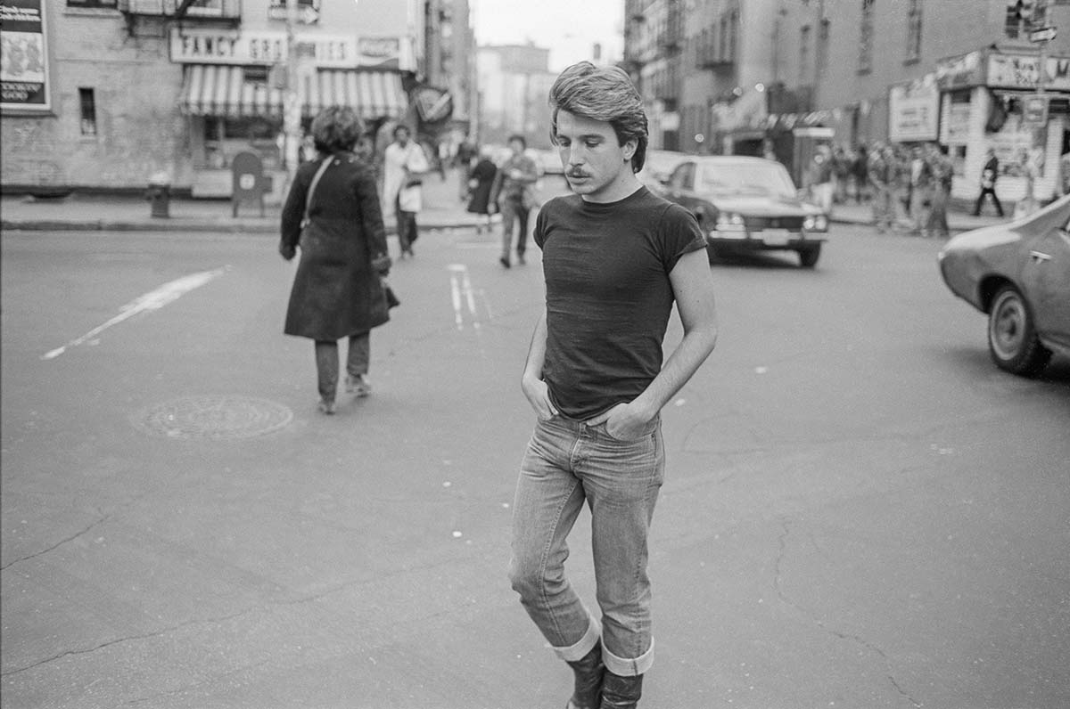 Man walking along Christopher street in New York, USA. He is looking at the floor and has his hands in his pockets.